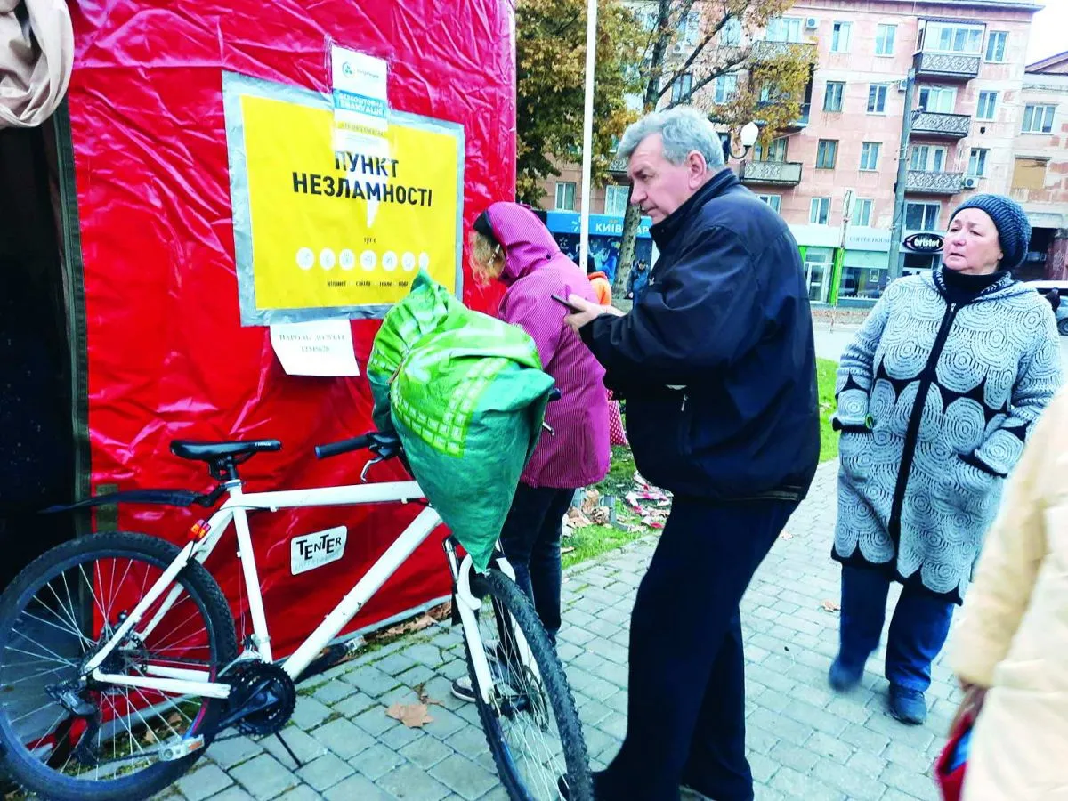 Літній херсонець переписує корисні номери телефонів біля «Пункту Незламності».